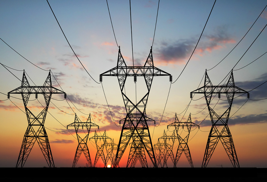 Electric transmission lines in front of a sunset.