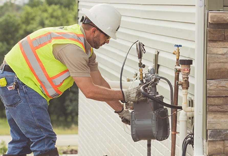 Gas technician working on a natural gas meter outside a home