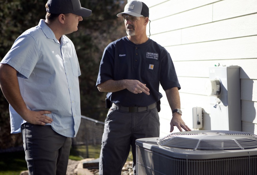 Technician inspecting an AC unit with customer