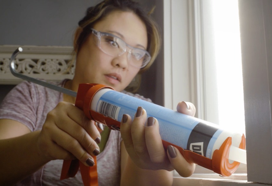 Woman caulking her window