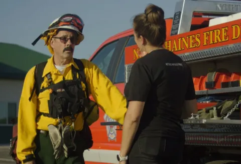 Volunteer firefighter talking to a women next to a truck